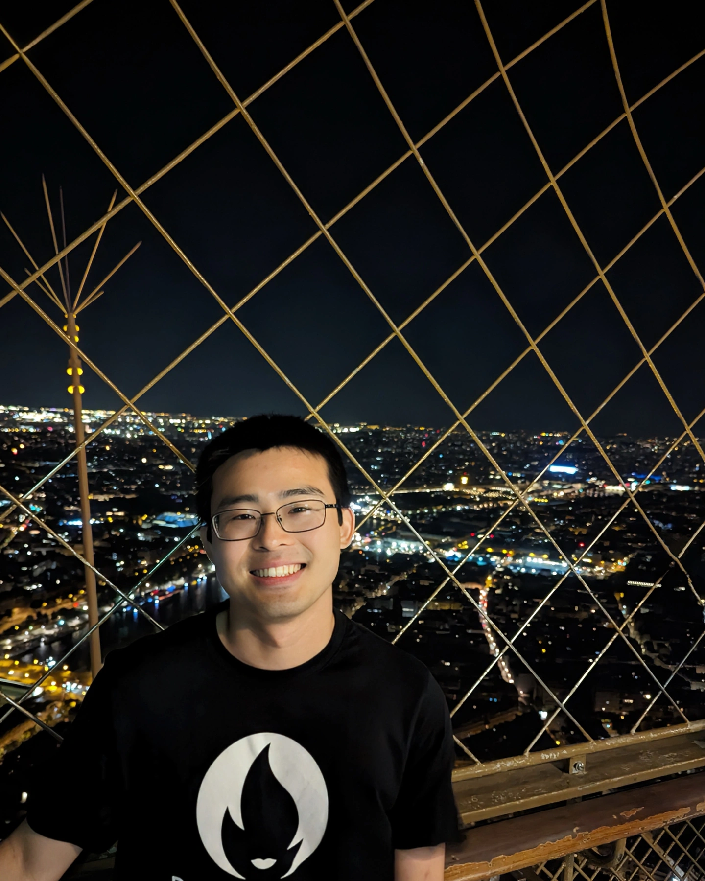 Before: Eiffel Tower selfie at night. Behind a wire fence, in the dark, in a graphic tee.